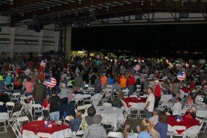 A large crowd of people are gathered around tables and chairs