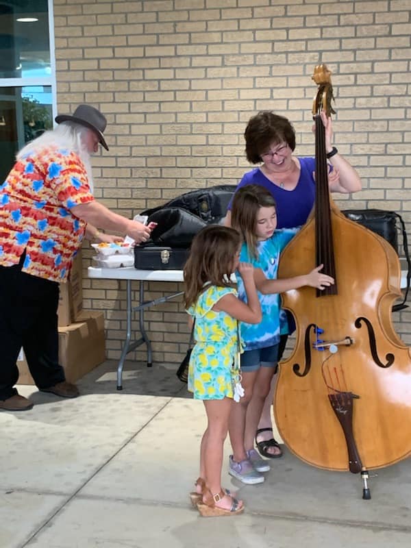 A group of people are standing around a double bass.