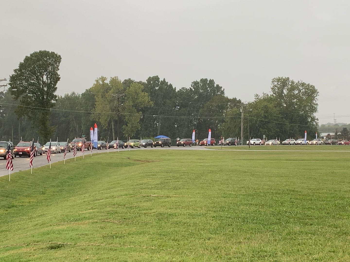 A row of cars are parked in a grassy field.