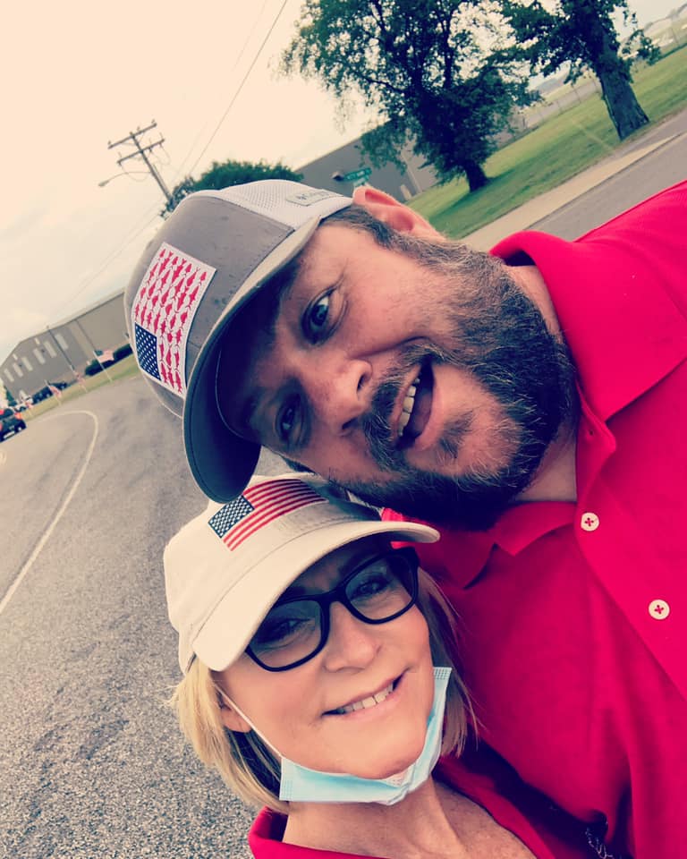 A man and a woman are posing for a picture on the side of the road.