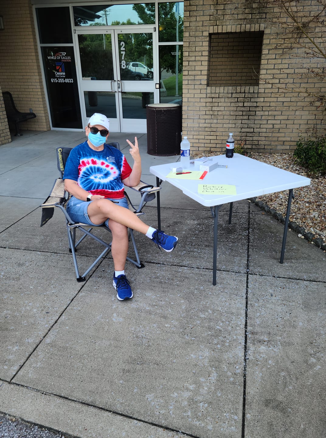 A man wearing a mask is sitting in a chair in front of a table.