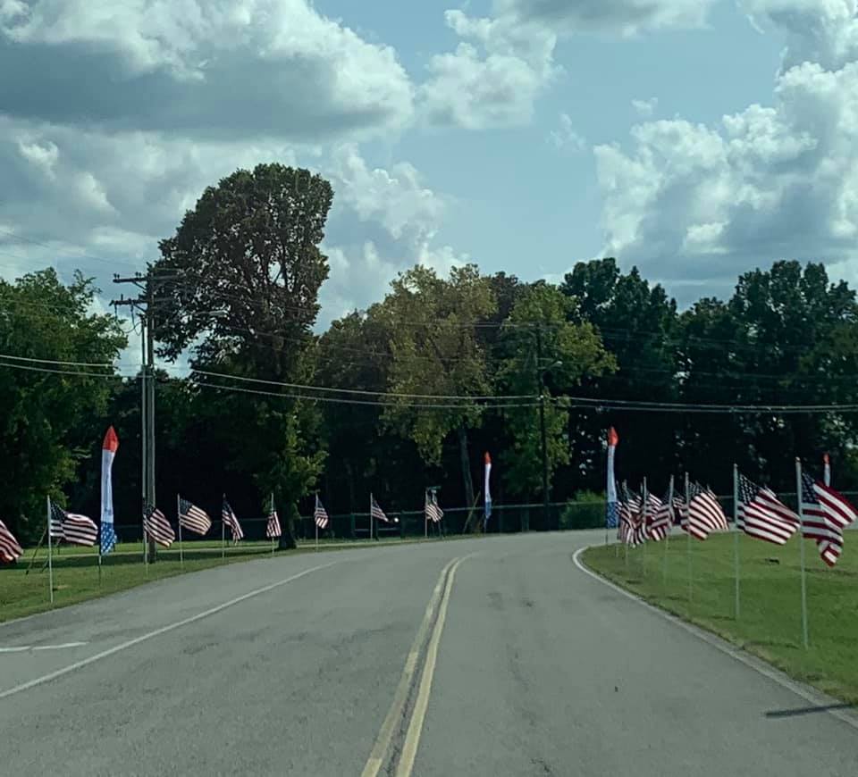 A road with many american flags on the side of it