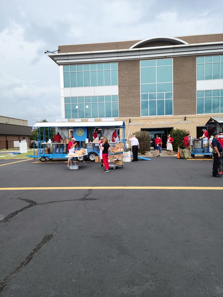 A group of people are standing in a parking lot in front of a large building