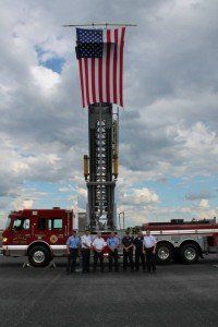 A group of firefighters standing in front of a large american flag