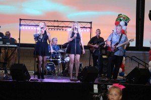 A group of people are standing on a stage singing into microphones.
