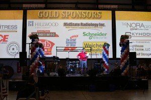 A man is standing on a stage in front of a large screen that says gold sponsors