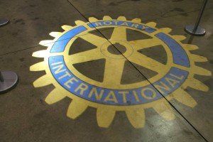 A yellow and blue rotary international logo on a concrete floor