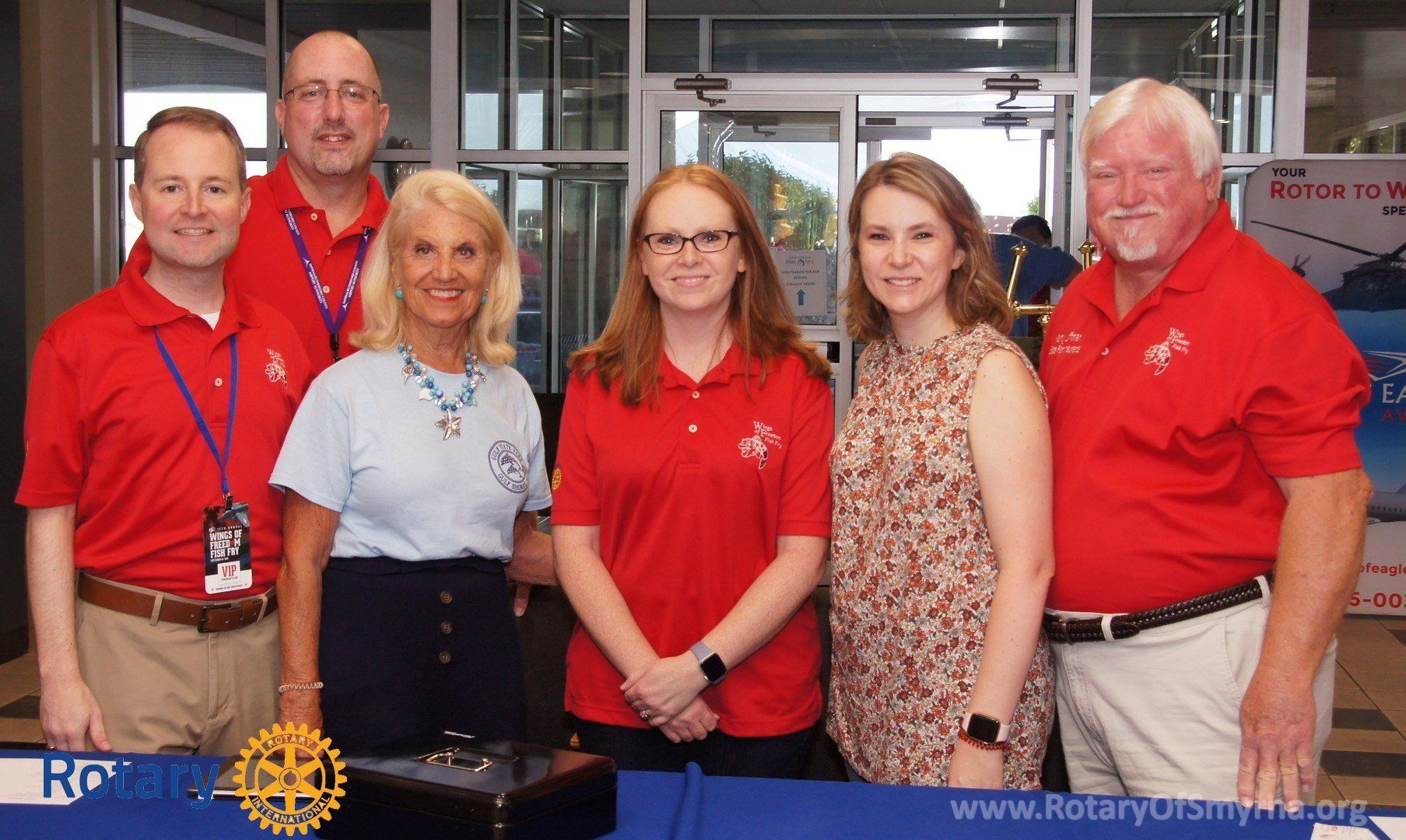 A group of people posing for a picture with a rotary logo in the background