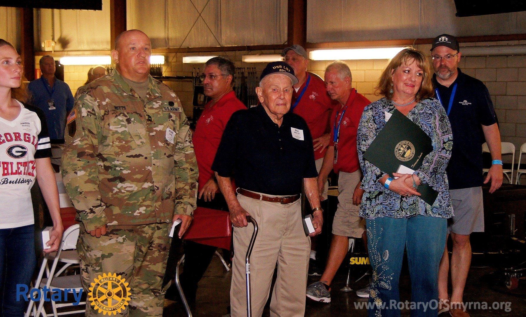 A group of people are standing in front of a sign that says rotary
