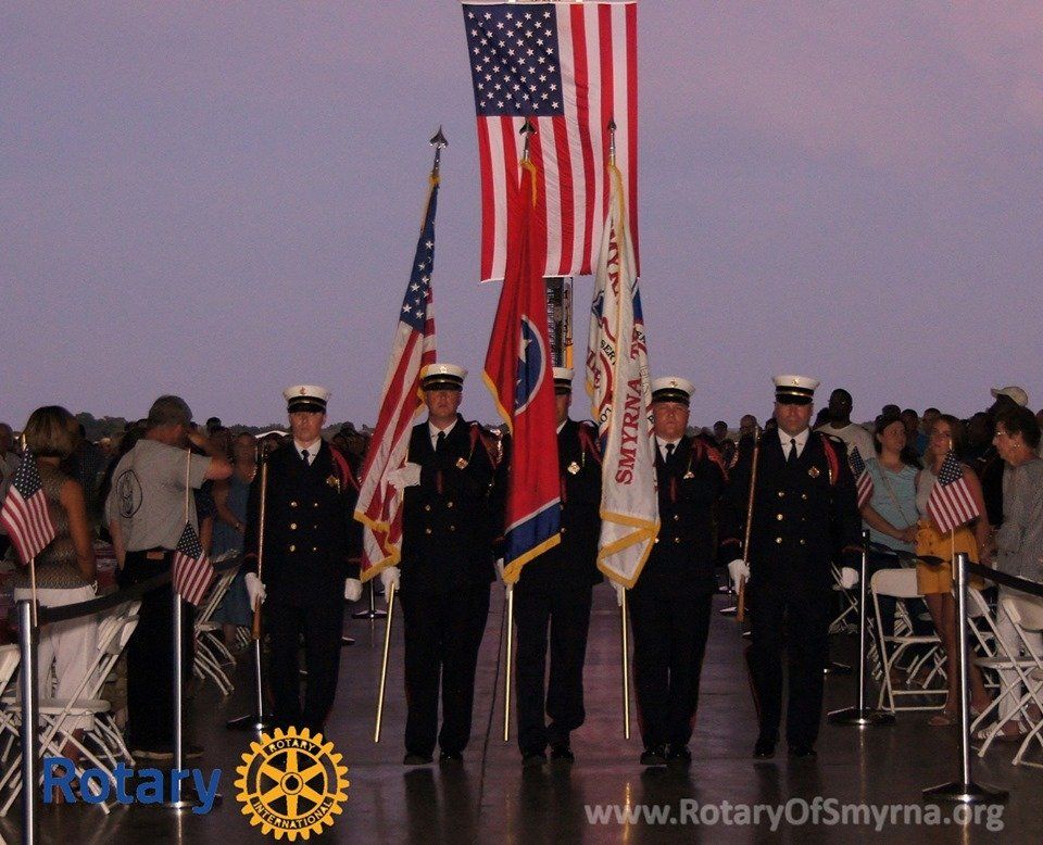 A group of men holding flags in front of a rotary logo