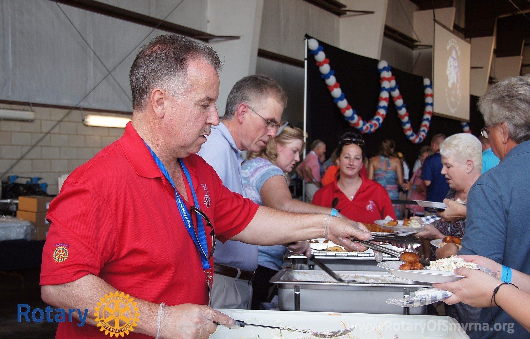 A man wearing a red shirt with the word rotary on it