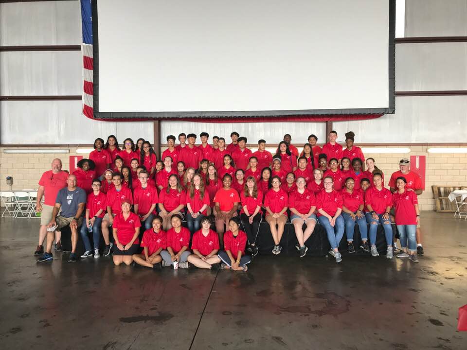 A large group of people are posing for a picture in front of a large screen.