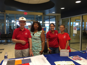 A group of people standing around a blue table