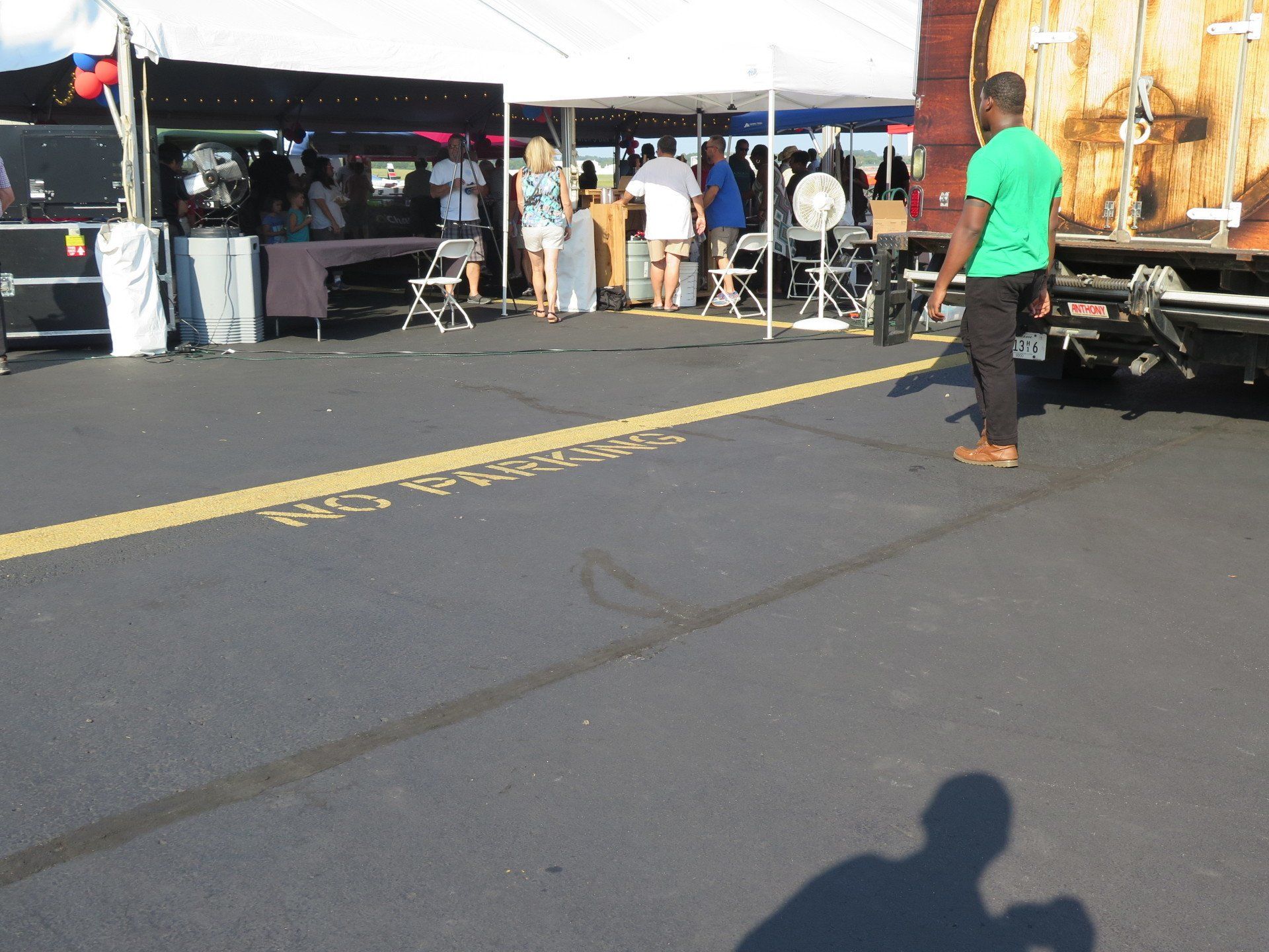A man in a green shirt is standing in a parking lot