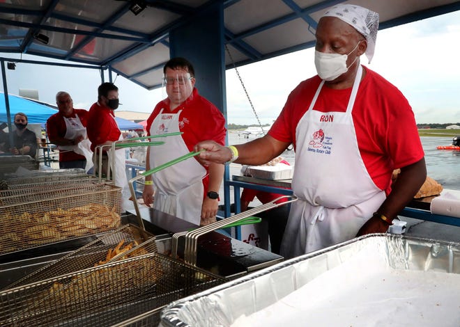 A man wearing a mask is cooking french fries in a fryer