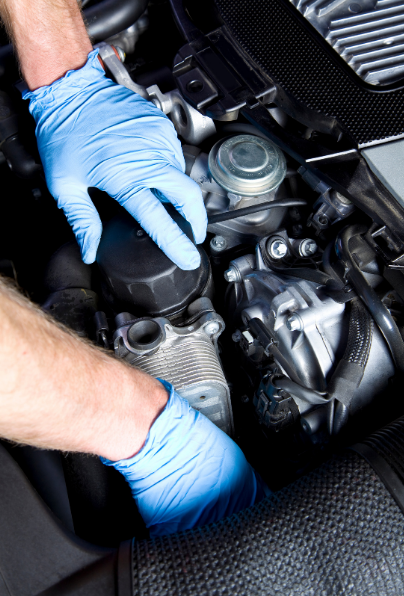 Gloved hands working on a car engine in a close-up view