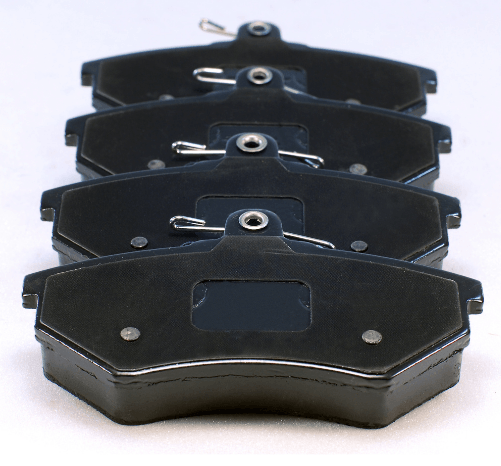 Stack of black automotive brake pads on a white background
