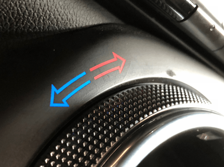 Close-up of a car dial with blue and red arrows indicating temperature direction
