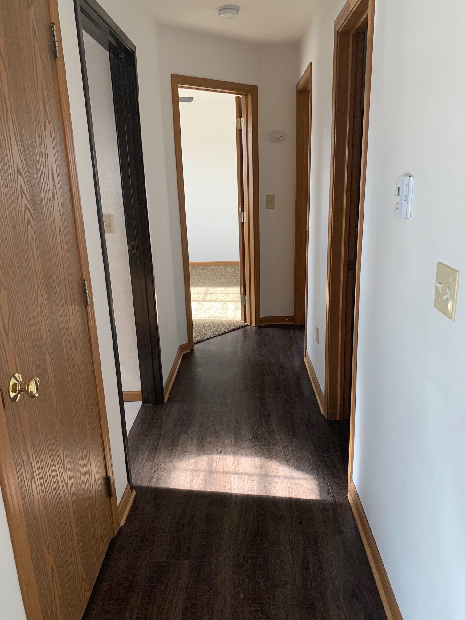 A hallway in a house with wooden floors and white walls