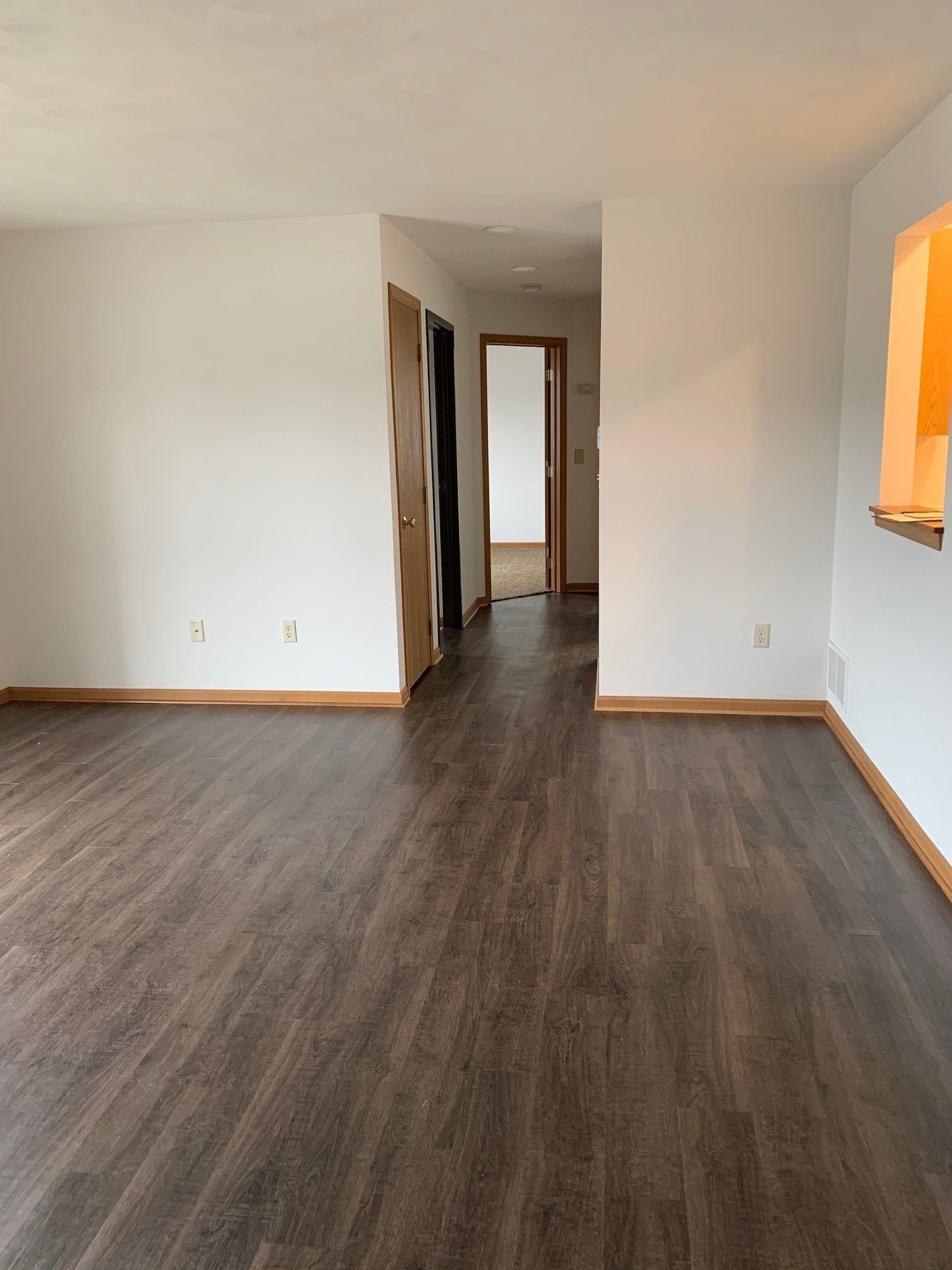 An empty living room with hardwood floors and white walls.