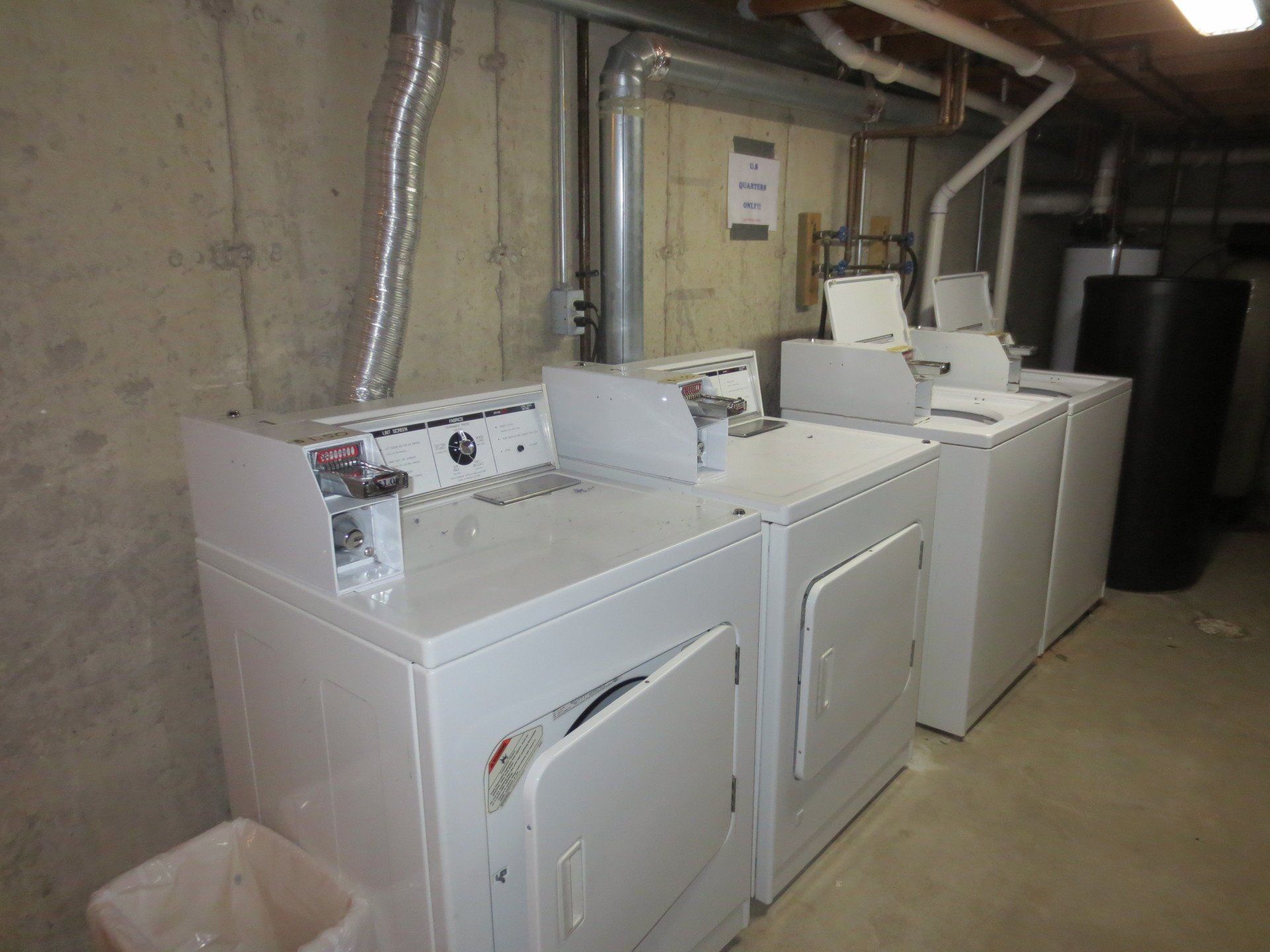 A row of white washers and dryers in a laundromat