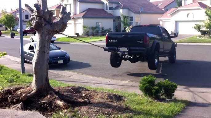 A truck is being towed by a tree in a residential neighborhood