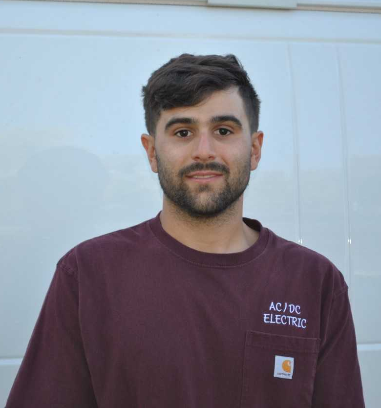 A man wearing a purple shirt that says ac / dc electric