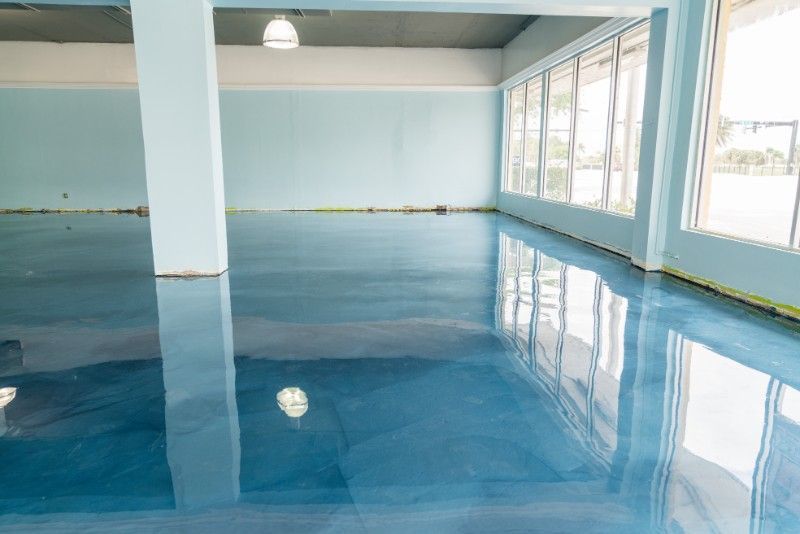 Empty indoor pool with blue water and large windows reflecting light