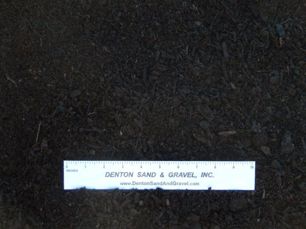 Dark soil with a ruler, presumably for measuring.