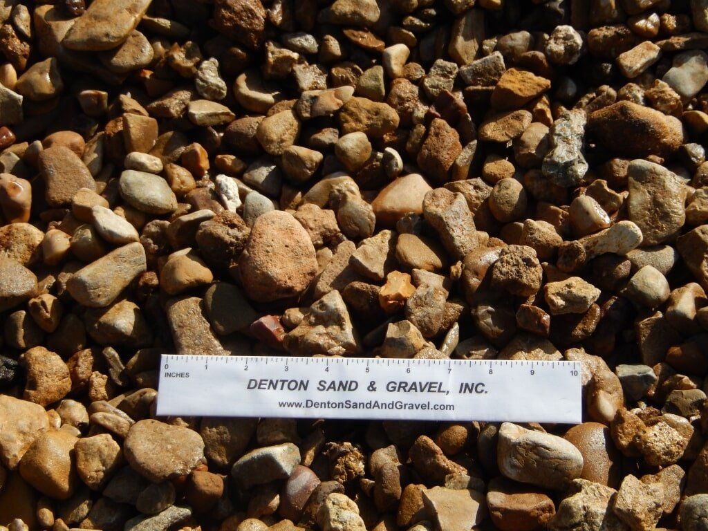 Gravel aggregate with various earth tones, a ruler for scale.