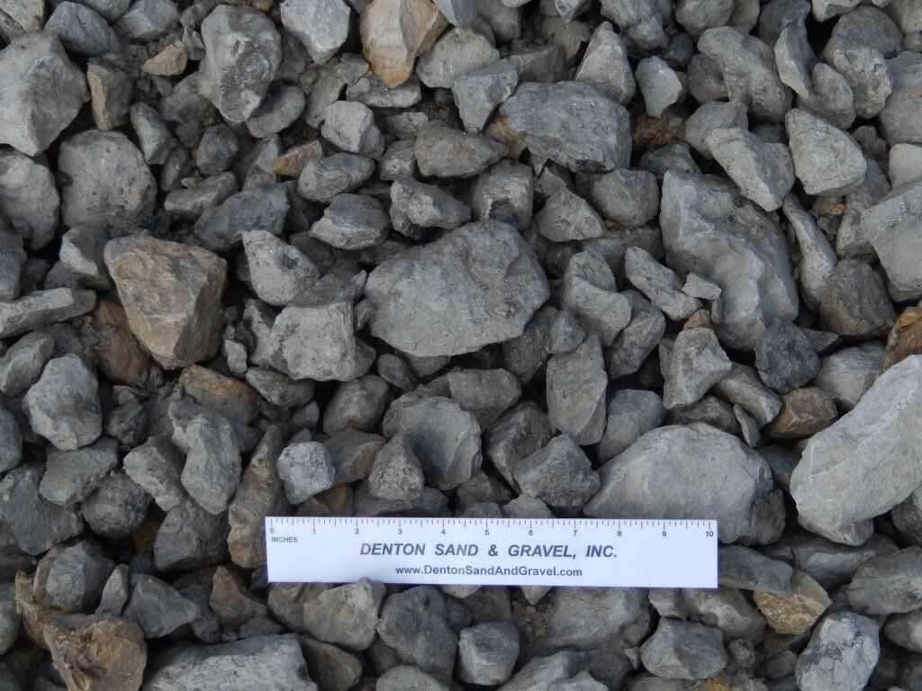 Gray and tan crushed stone aggregate with a ruler for scale.