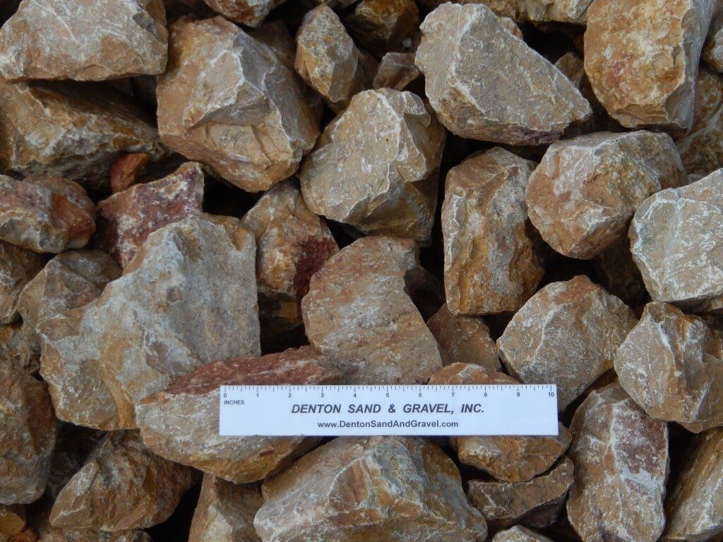 Tan and reddish-brown landscaping rocks of various sizes, with a ruler for scale.