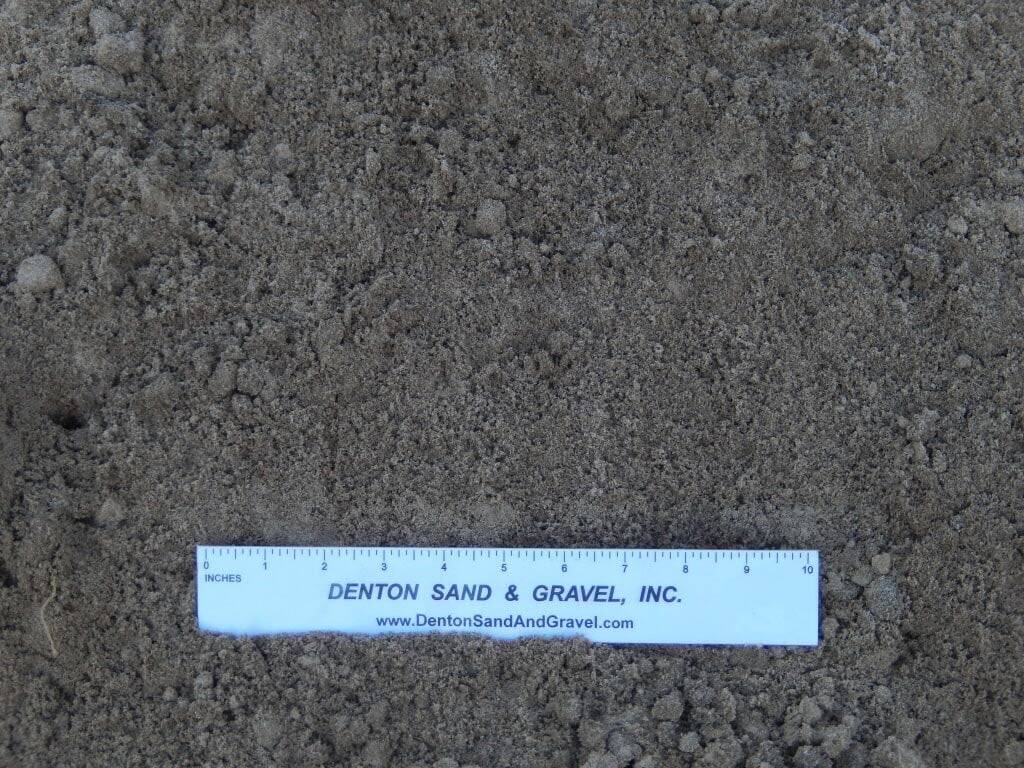 Close-up of brown sand with a ruler from Denton Sand & Gravel.