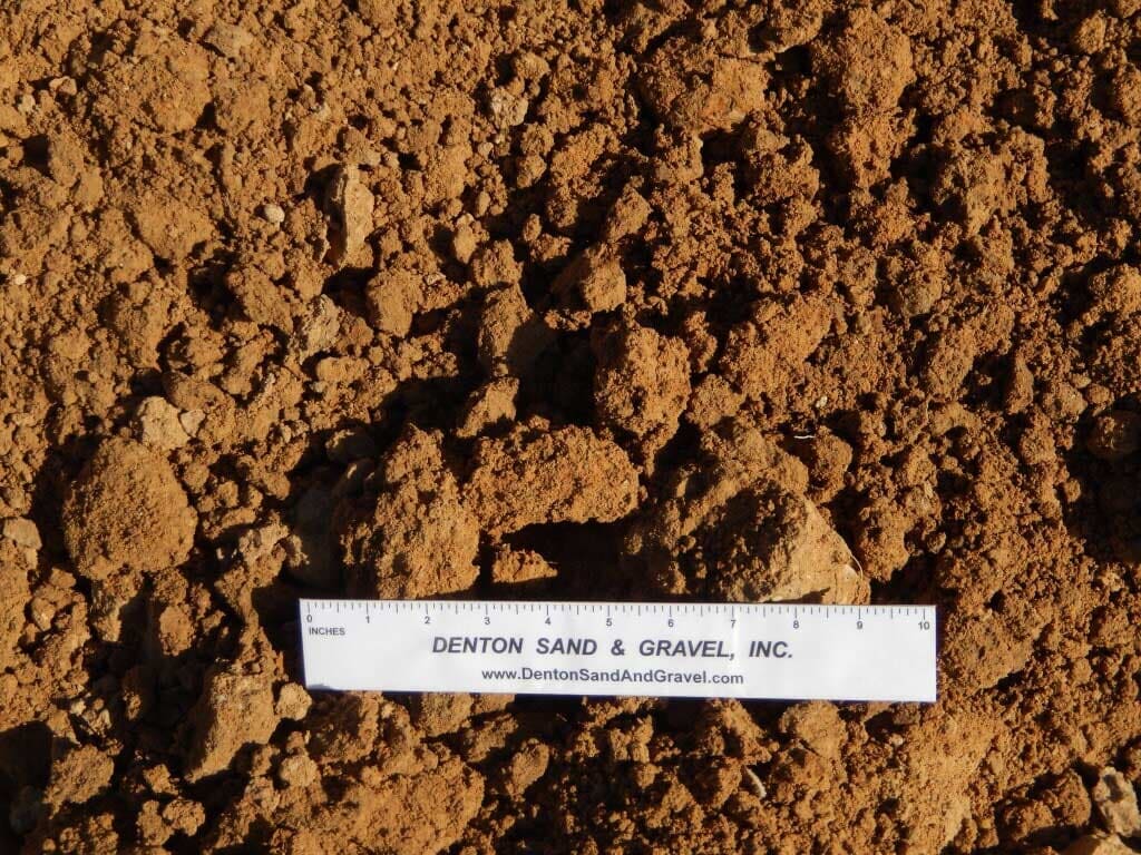 Brown soil with a ruler.