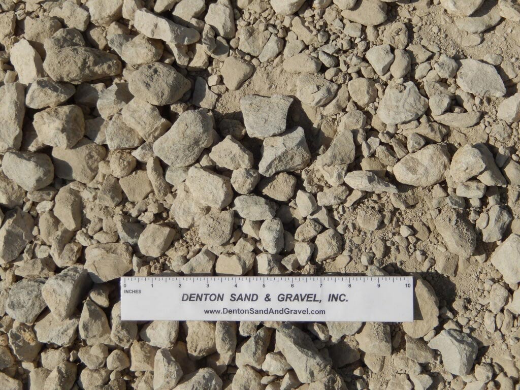 Crushed gravel aggregate with a ruler for scale. Light brown, beige colored rocks.