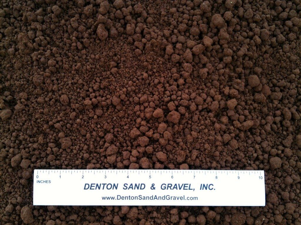 Dark brown soil, with a ruler from Denton Sand & Gravel for scale.