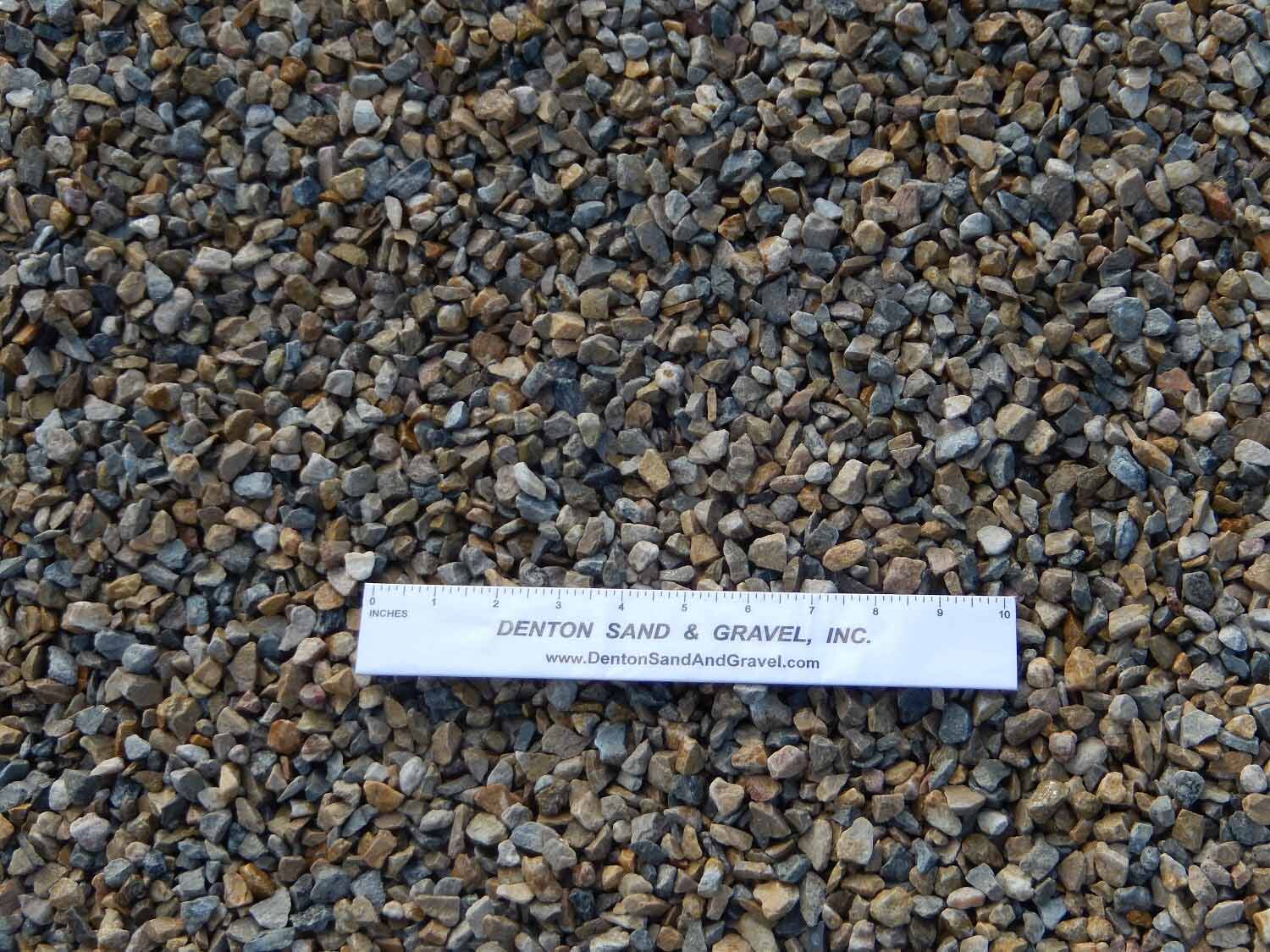 Close-up of gravel stones with a white ruler that reads 