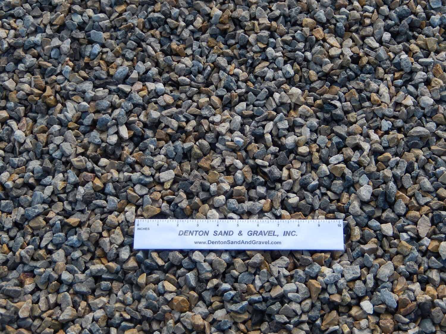 Close-up view of small gravel rocks in various colors, with a ruler placed across them.