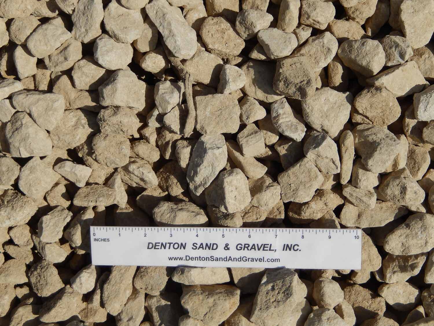 Pile of light-colored gravel with a ruler from Denton Sand & Gravel Inc.