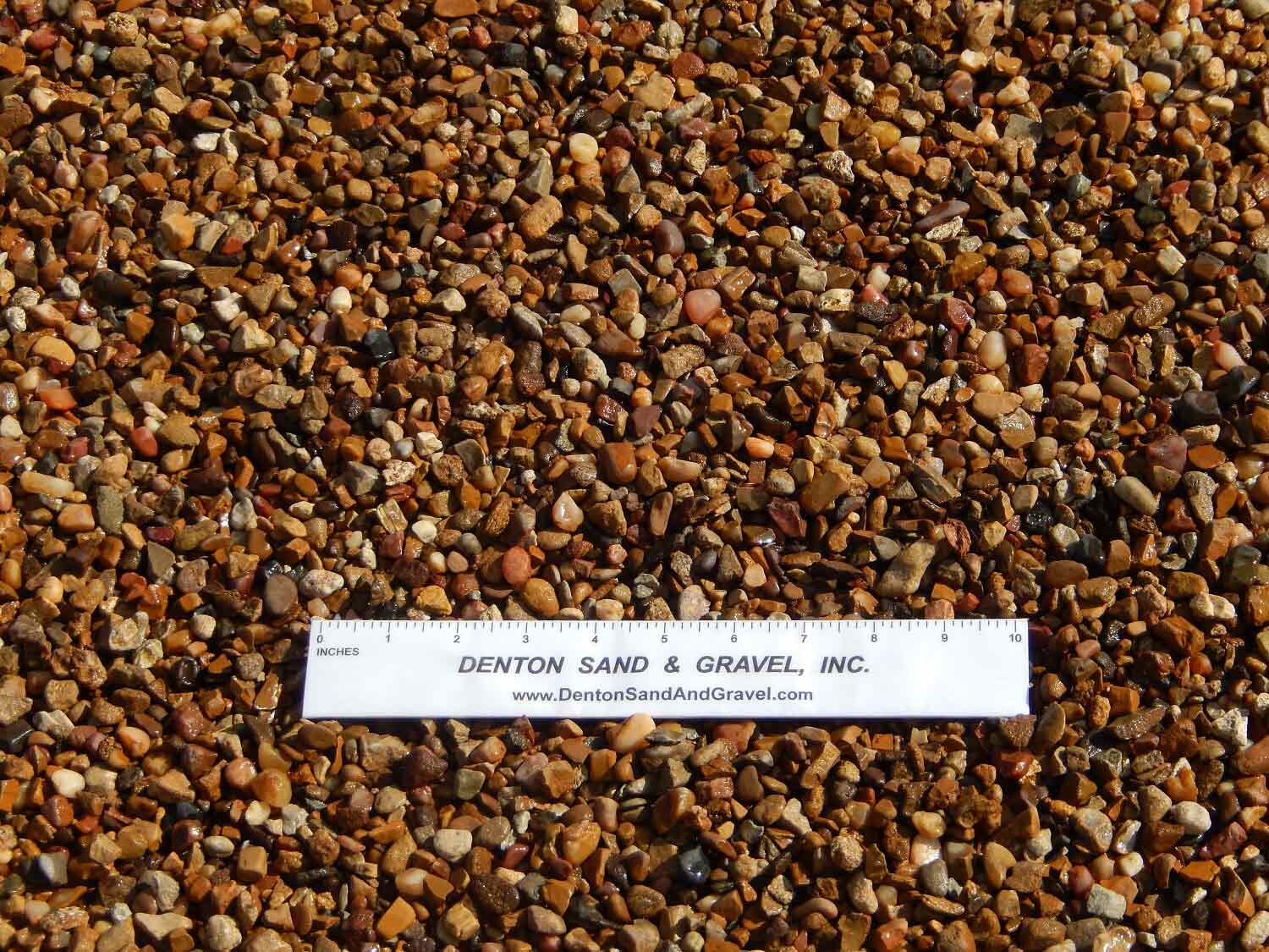 Small, rounded gravel of various earth-tone colors with a ruler for scale.