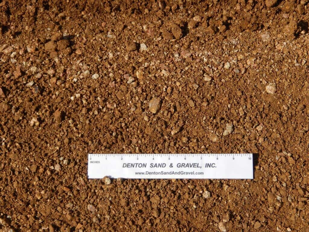 Brown soil and gravel with a ruler laid across it, demonstrating the size and texture.