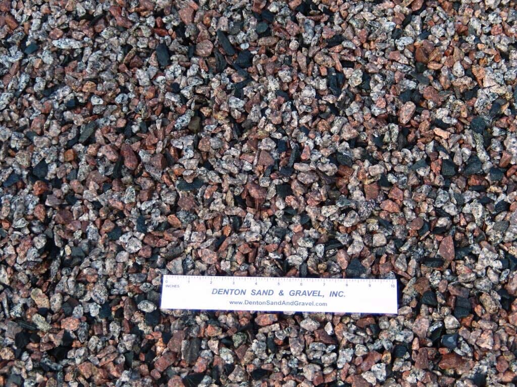 Gravel aggregate, with red, gray, and black stones, and a ruler with 