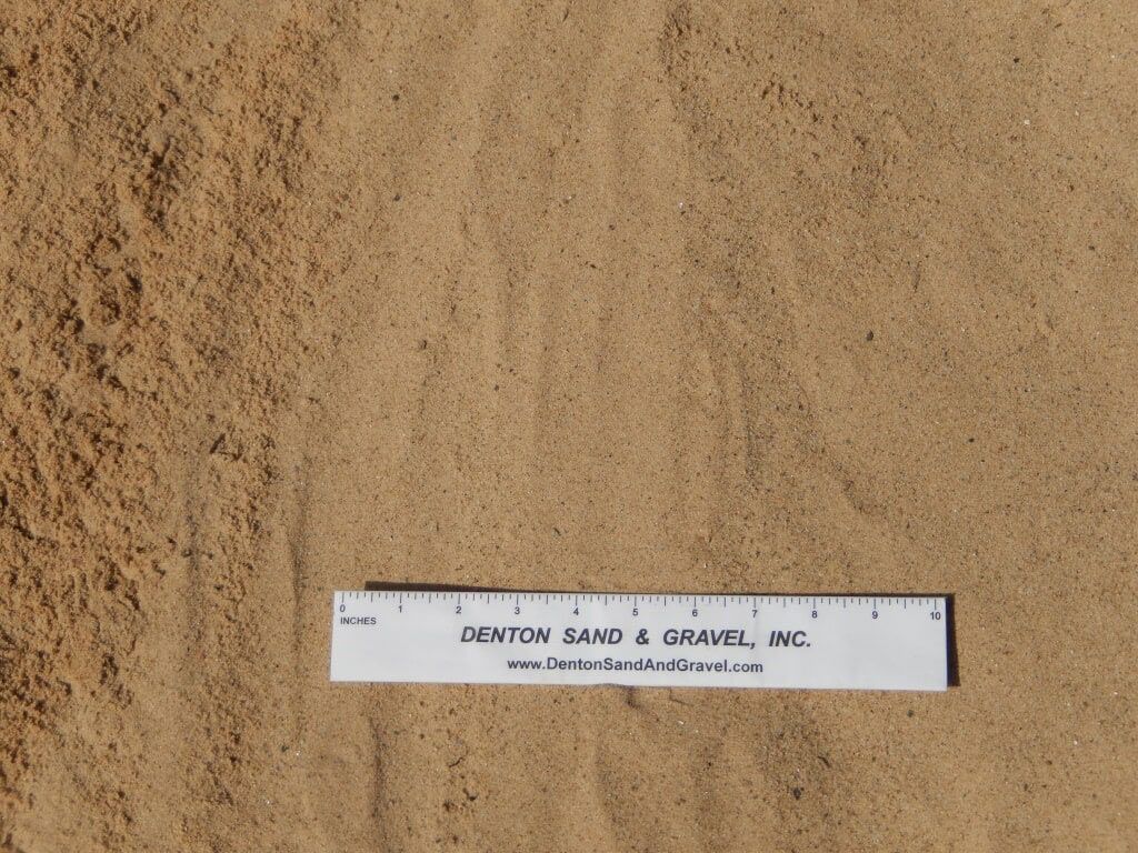 Tan sand with a white ruler that has black text.