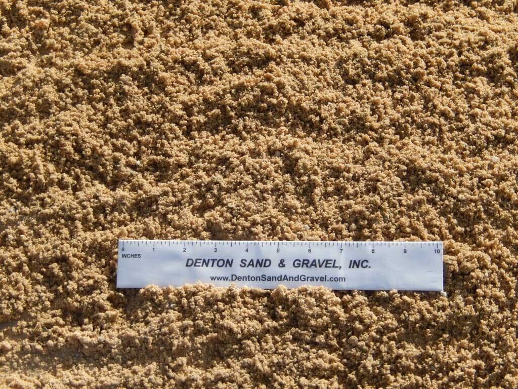 Tan sand with a white ruler from Denton Sand & Gravel.
