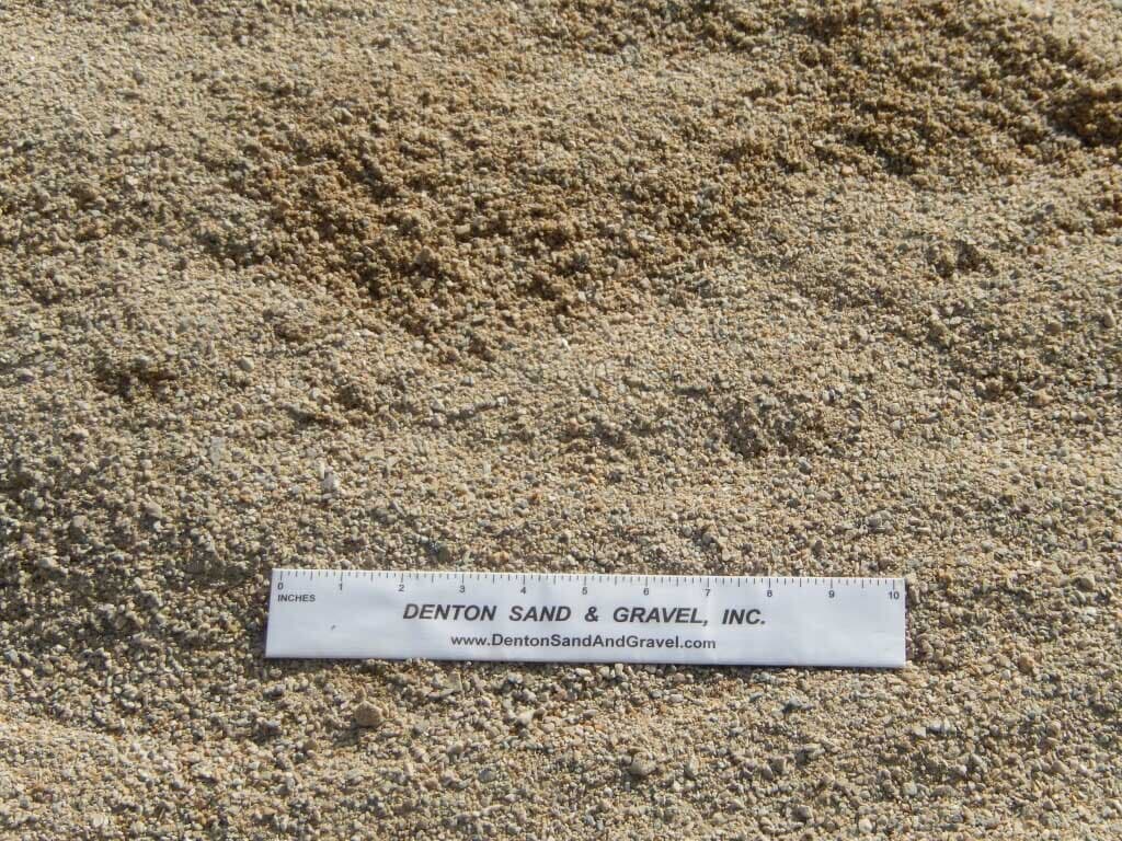 Sand, close-up with a ruler for scale; tan and beige colors.