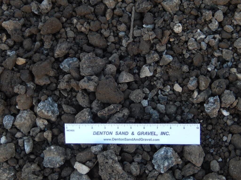 Gravel and sand mix, various sizes, shades of brown and gray. White ruler with business name.