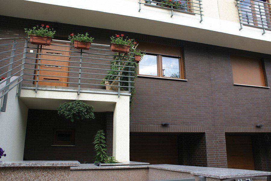 Brown brick building with balconies, planters, and garage doors.