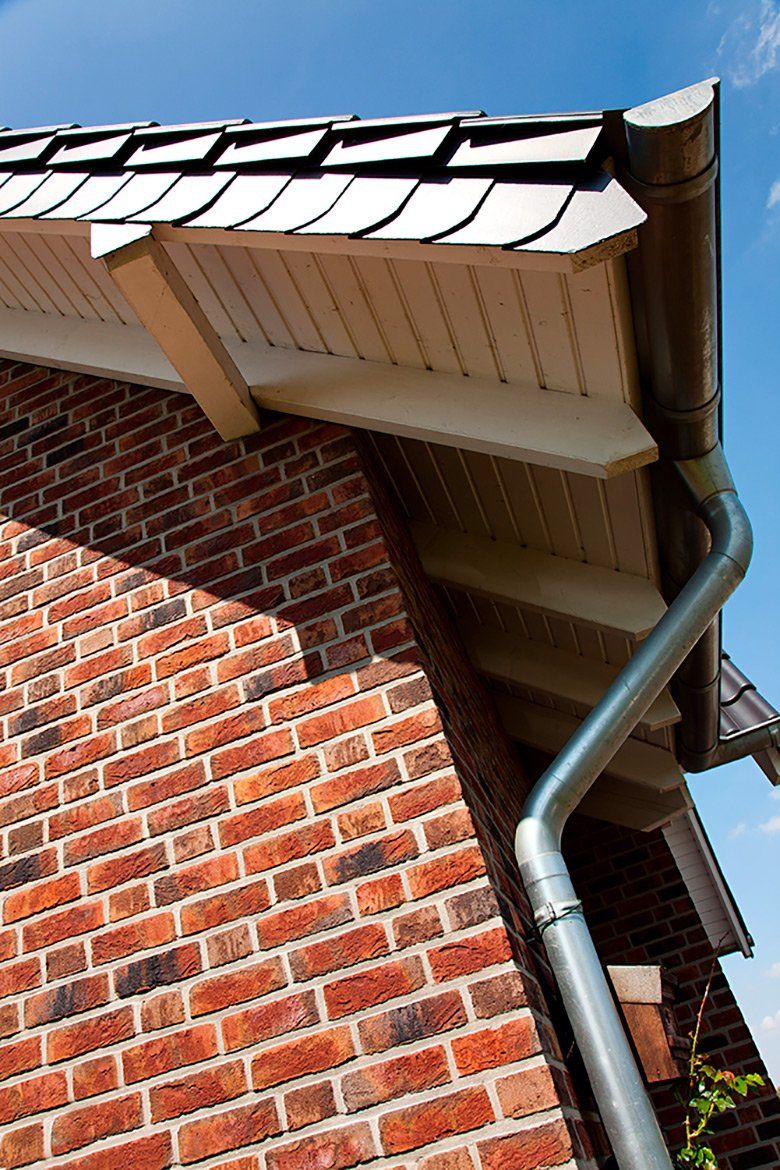 Brick wall with roofline, gutter and downspout.