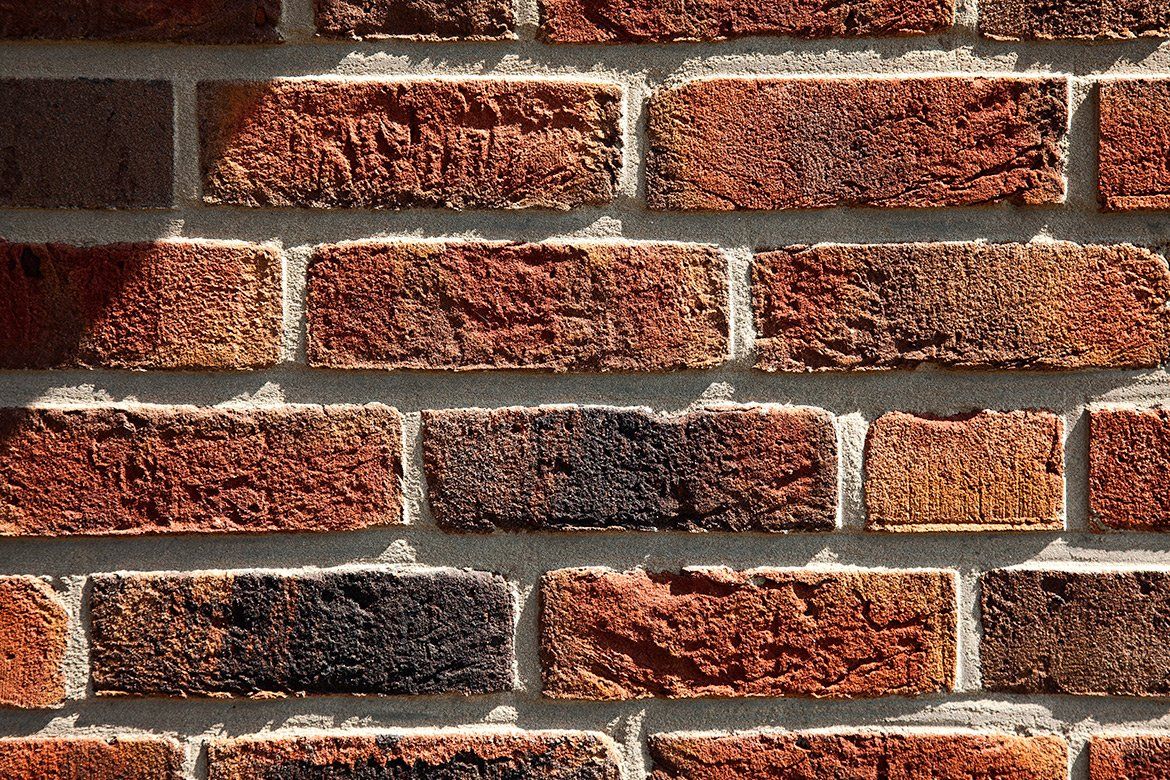Close-up of a brick wall, red and brown bricks with white mortar in horizontal rows.