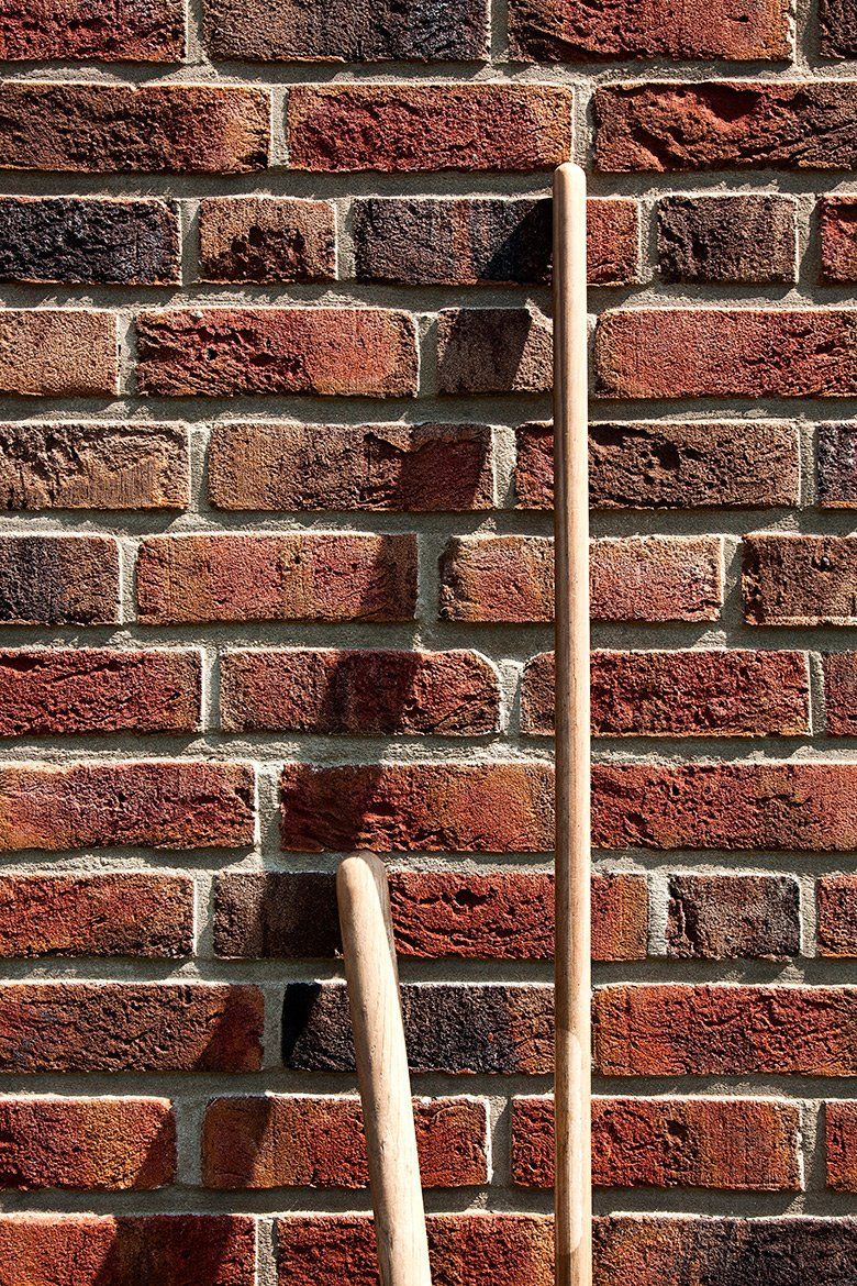 Two wooden poles against a brick wall.